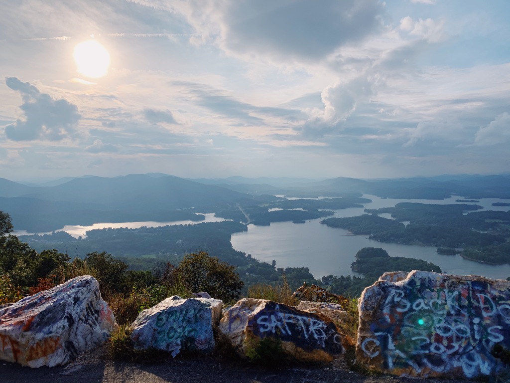 the view of lakes, trees, and mountains from Bell Mountain with graffiti covered rocks in the foreground