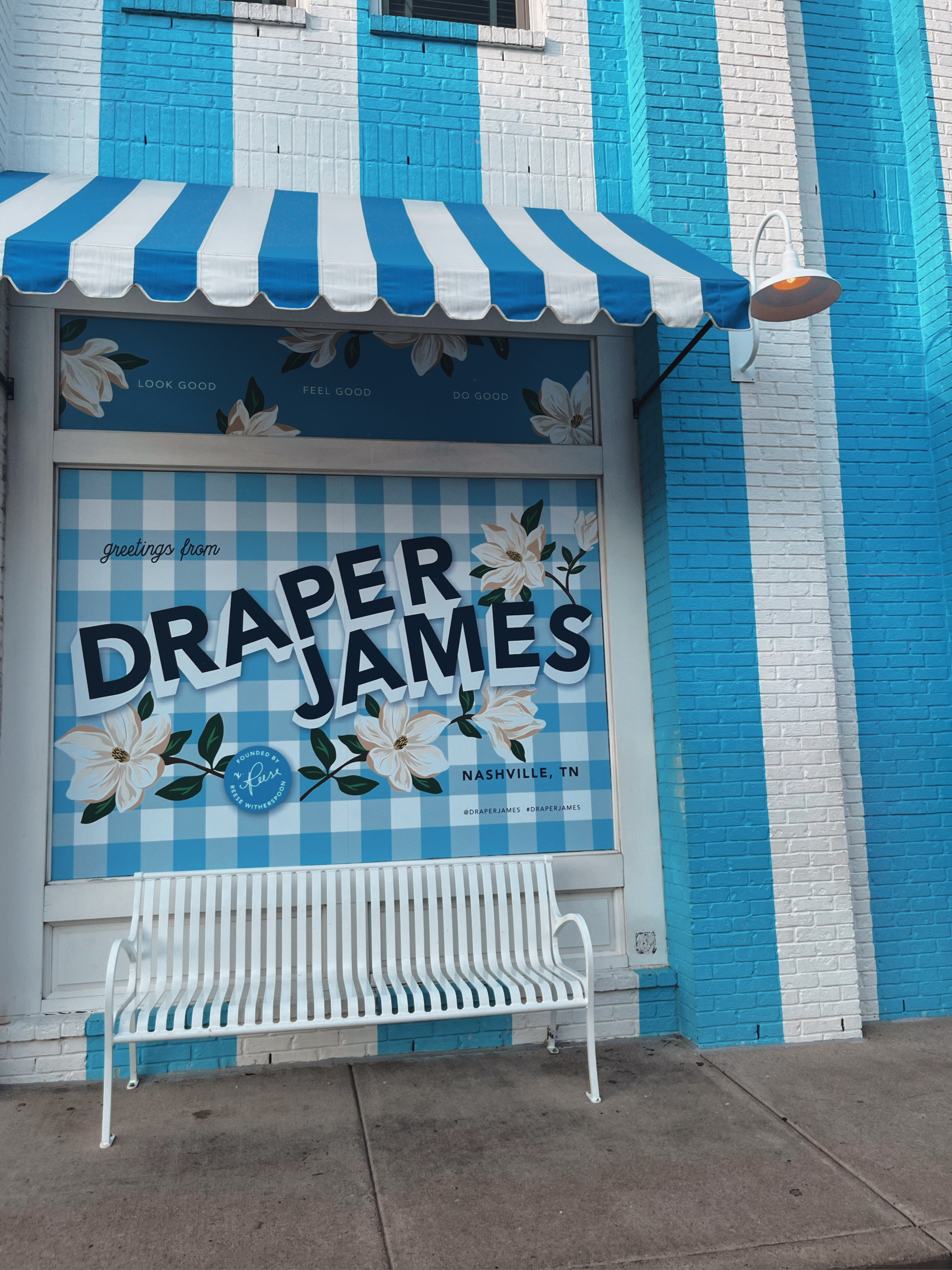 blue and white striped wall and a white bench, window says "Draper James"