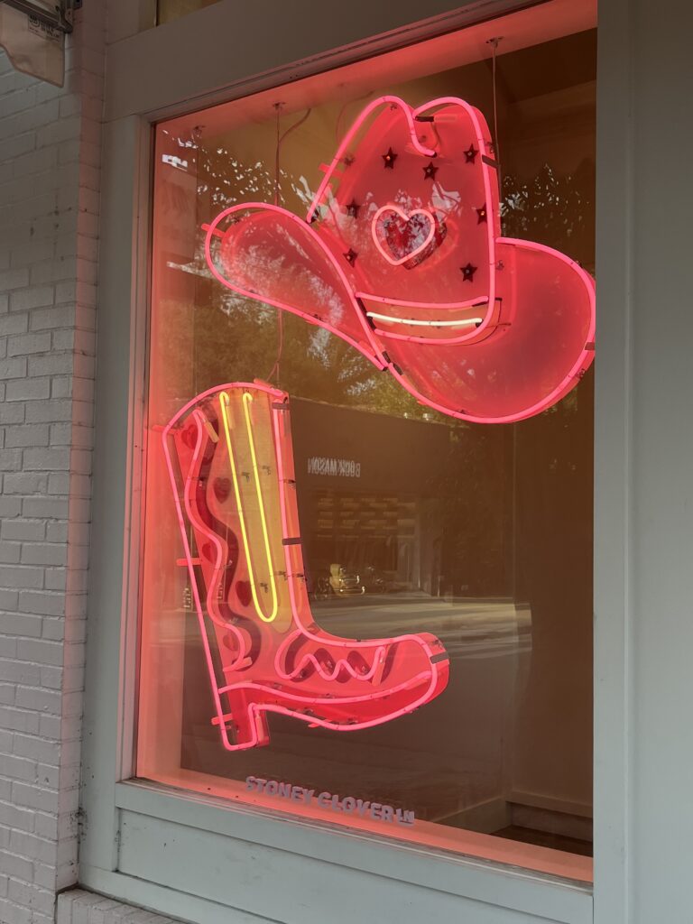 neon signs of a pink cowboy hat and a cowboy boot
