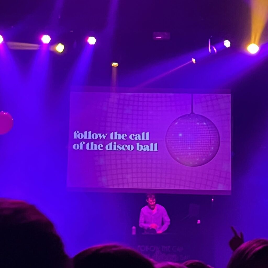 DJ infront of a purple screen that says "follow the call of the disco ball"