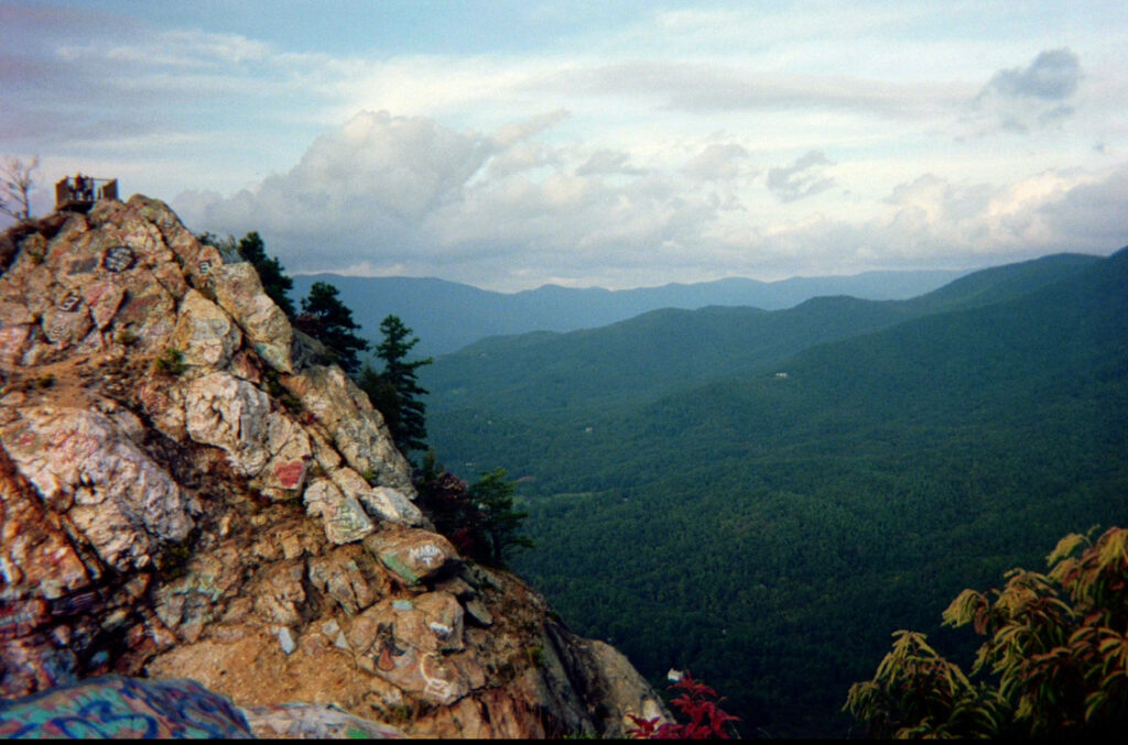 the view of trees and mountains from Bell Mountain with graffiti covered rocks in the foreground