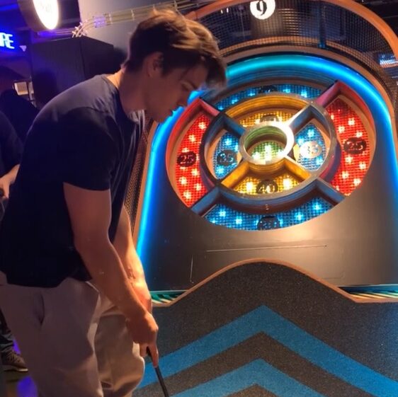 a man about to hit a golfball on a course that looks like a bullseye game