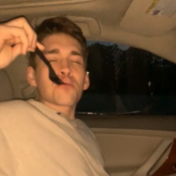 a guy with a black plastic fork in his mouth