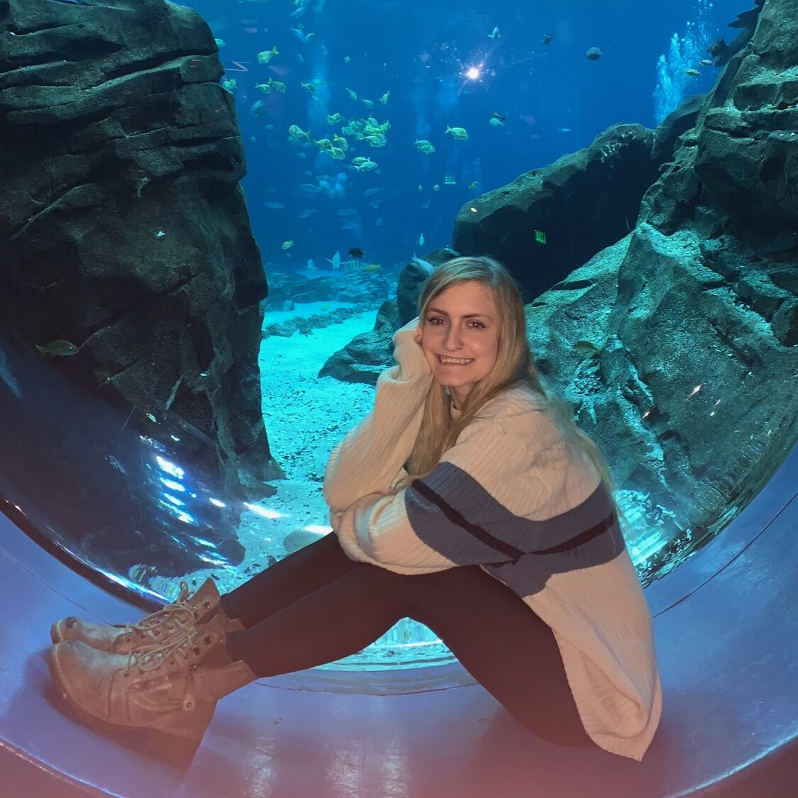 A girl sitting infront of a tank at the Georgia Aquarium 