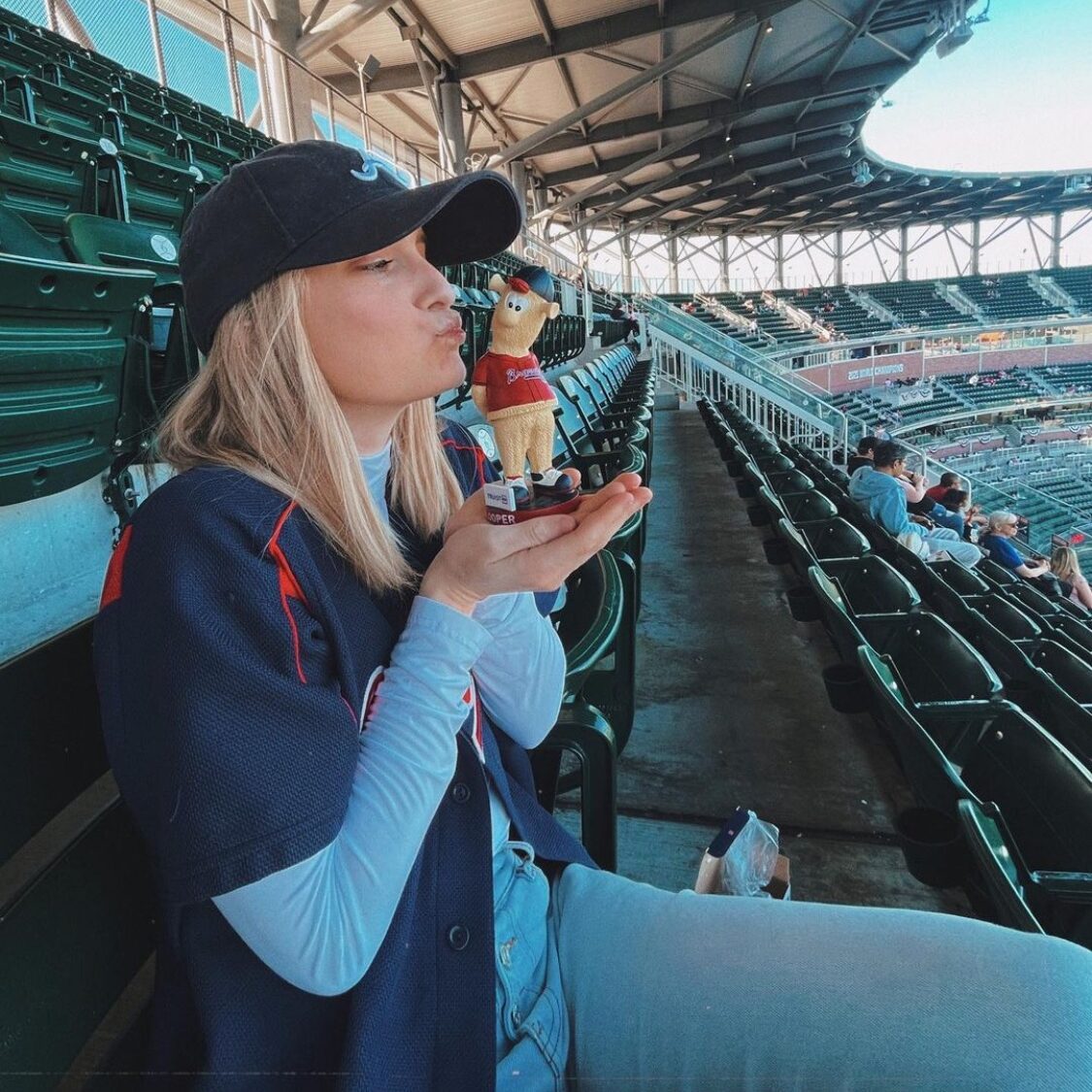 a girl pretending to kiss her Blooper bobblhead at an Atlanta Braves game 